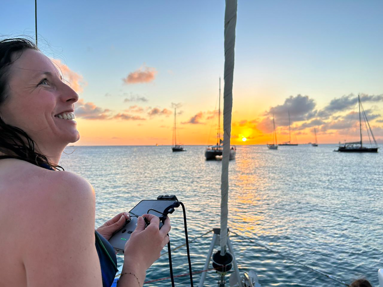 Femme pilotant un drone au dessus de la mer au coucher de soleil